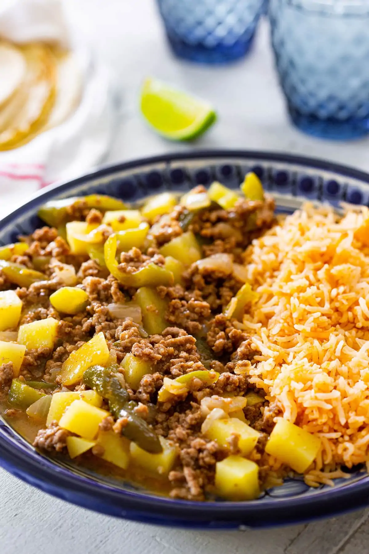 Mexican picadillo with potatoes on a blue plate with rice.