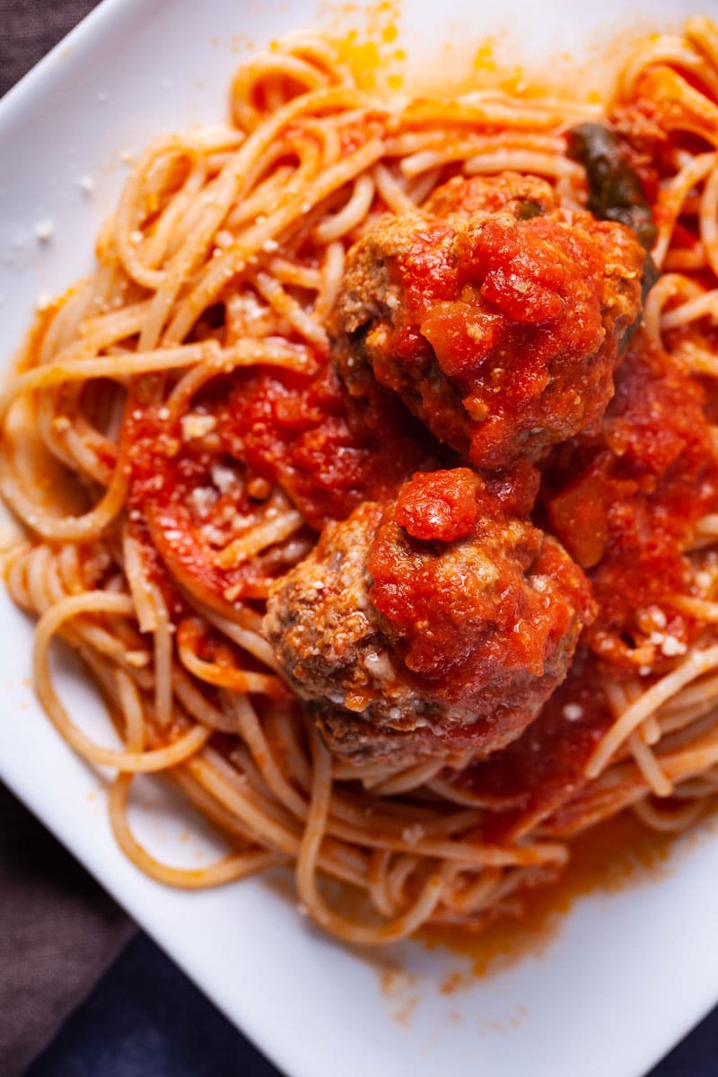 Italian meatballs with pasta on a white plate.