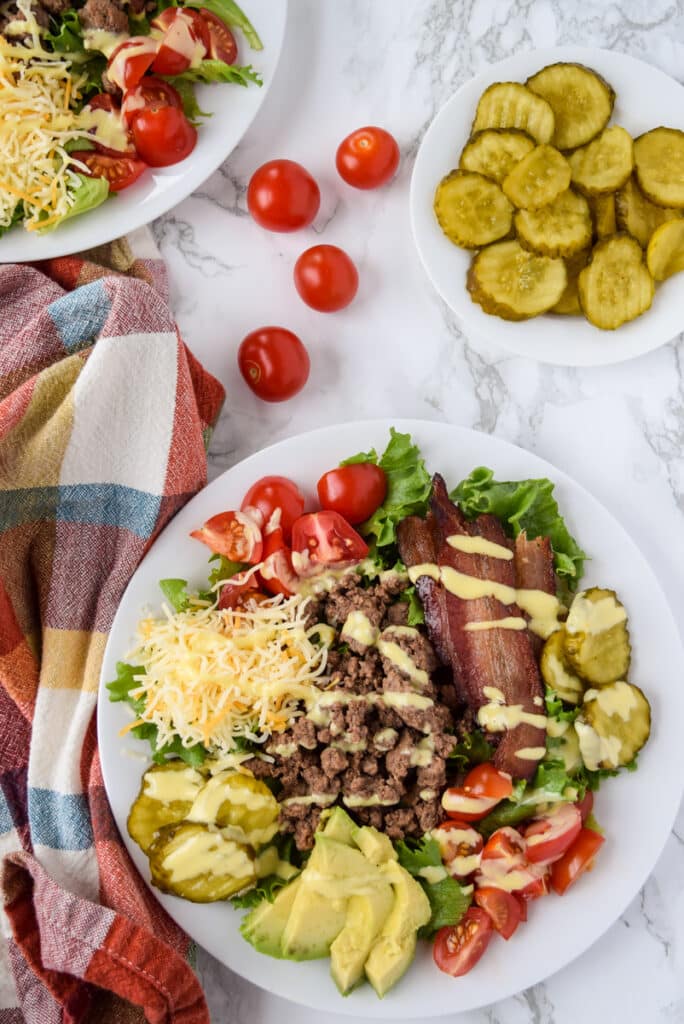 Bacon cheeseburger salad with ground beef, tomato, lettuce, cheese, and pickles.