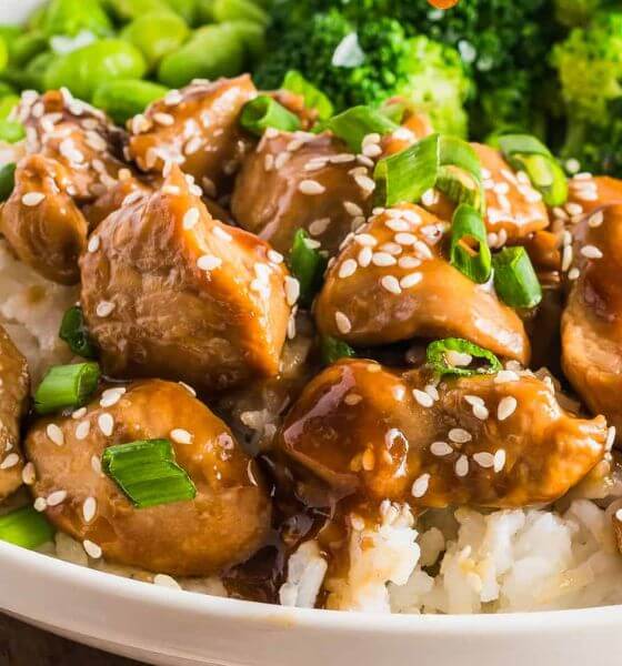 Teriyaki chicken over rice in white bowl with broccoli