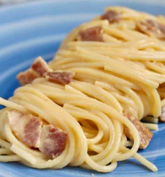 Pasta with egg and bacon on blue plate