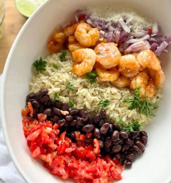 Shrimp bowl with rice, beans, onions, tomatoes in white bowl